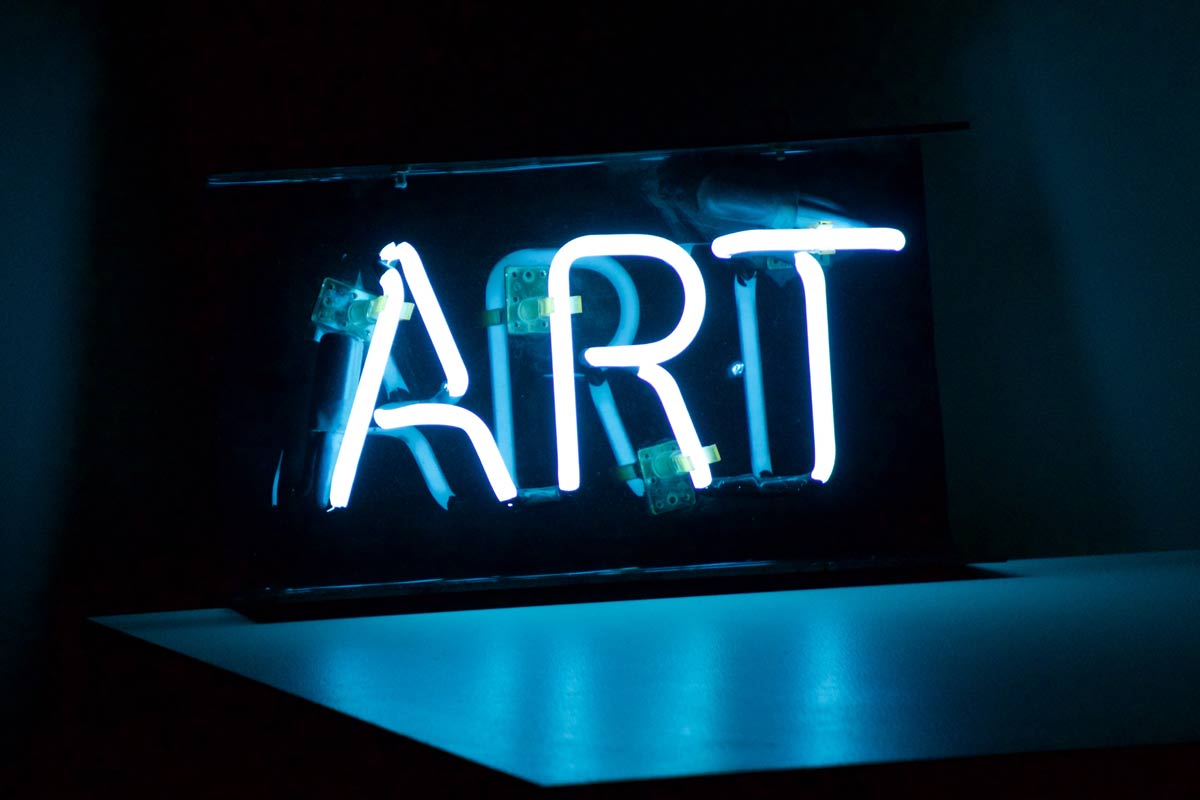 Neon white sign that reads, "ART"