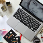 Aerial photo of laptop with art tools surrounding it