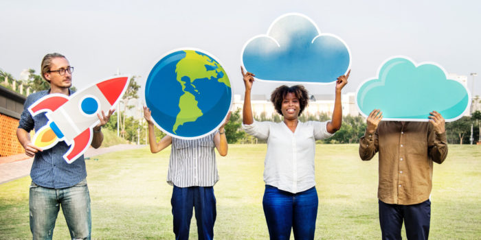 Young professionals hold up cutout illustrations of rocket ship, Earth, and clouds